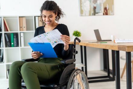 woman in wheelchair smiling and reviewing charts on paperwork