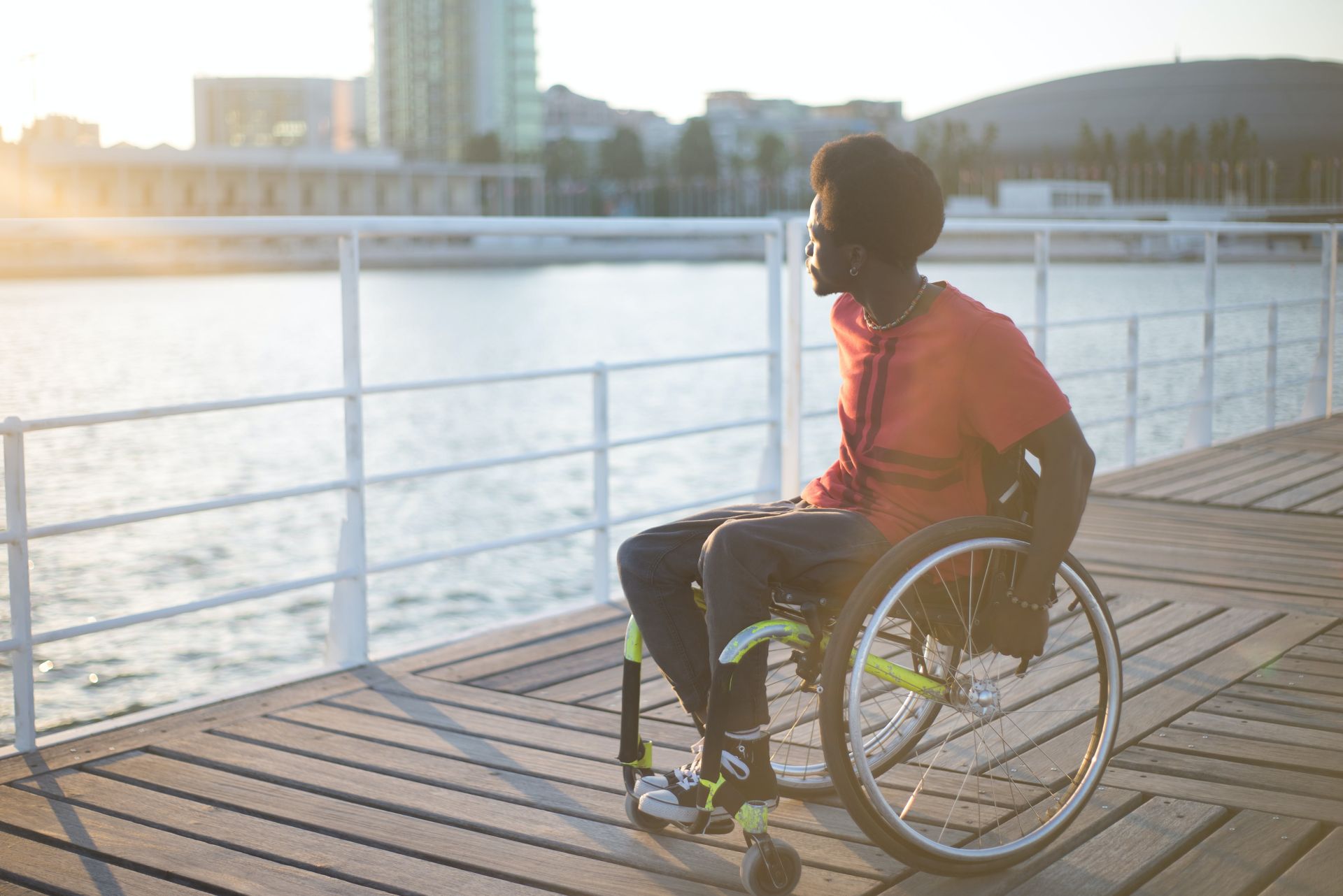 Man on Wheelchair Looking Away from a bridge onto water, looking contemplative about his future