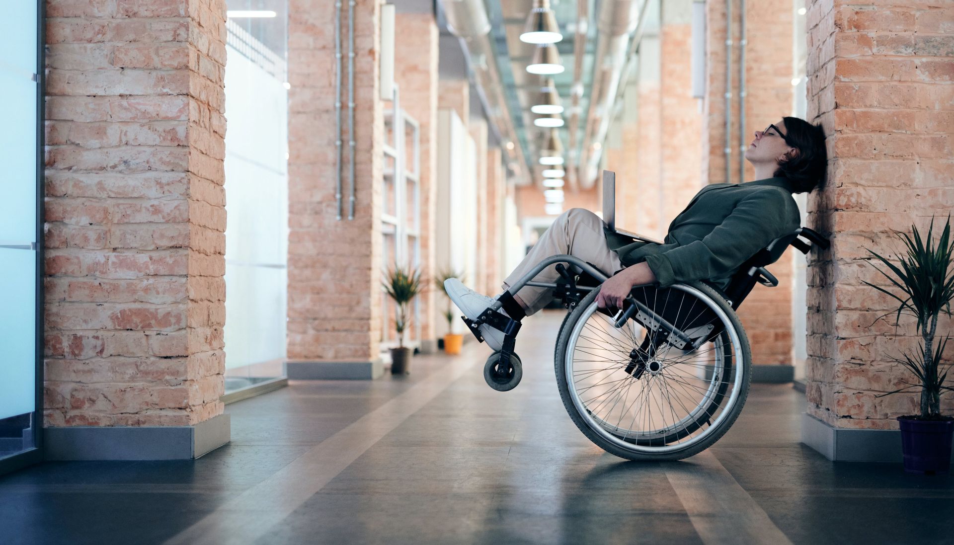 Photo of Woman Sitting on Wheelchair While Leaning on Wall